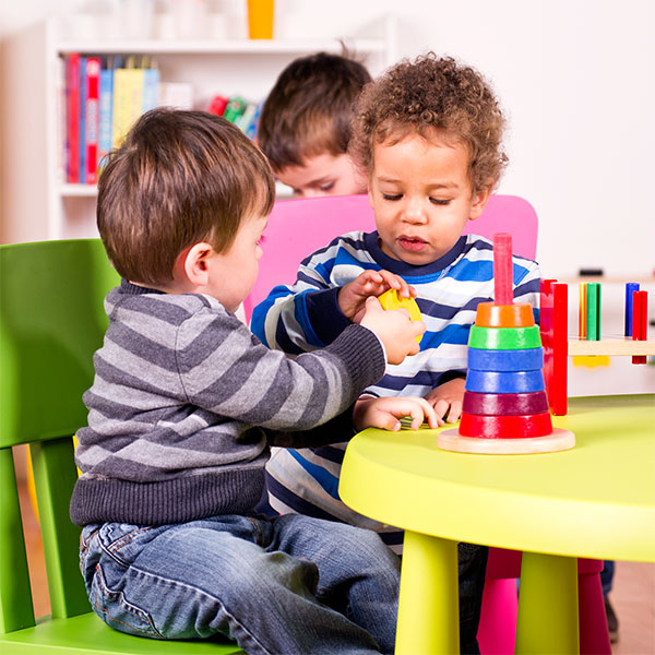 Children playing with stacking blocks at a brightly colored table